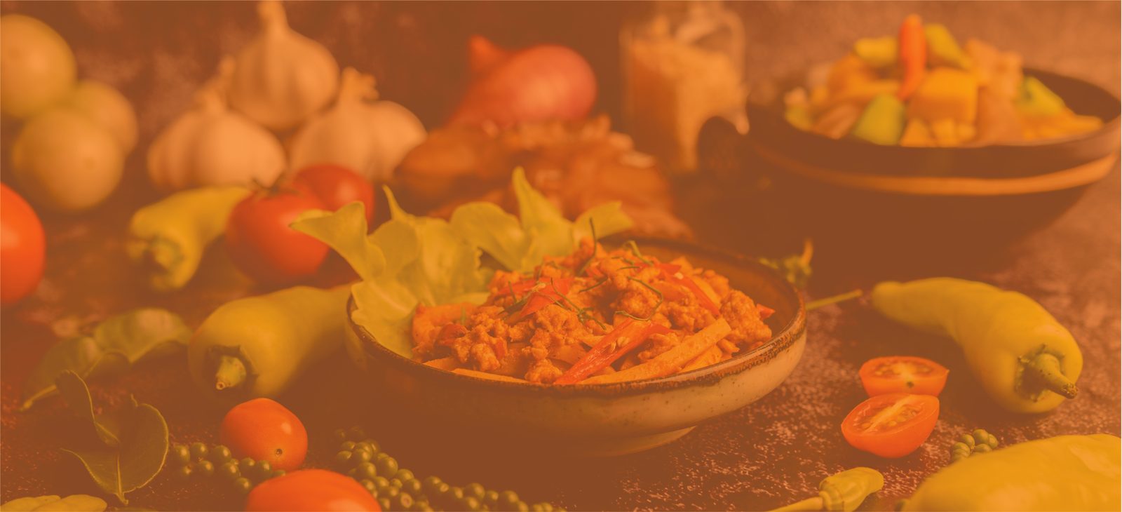 Fresh vegetables, peppers and a cooked dish on a rustic table